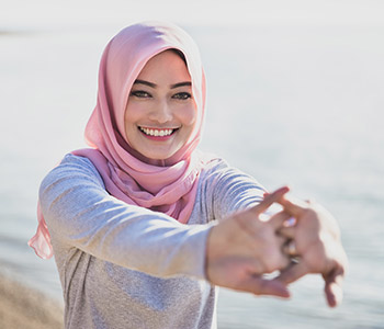 Woman standing by the water, streching her hands