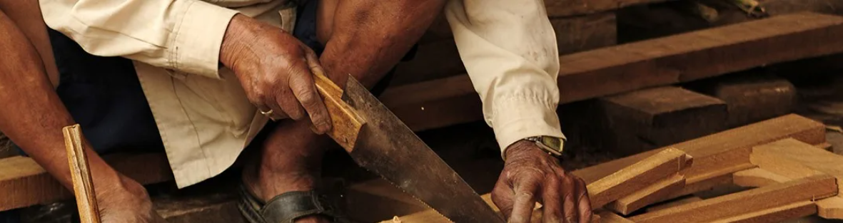 hombre agachado cortando un pedazo de madera
