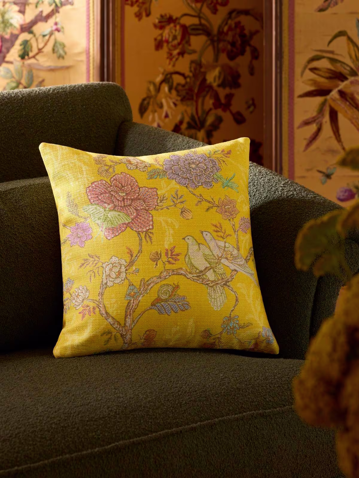 Image of forest green sofa with the Ruggable x Iris Apfel Vibrant Garden Citron Yellow Woven Throw Pillow.