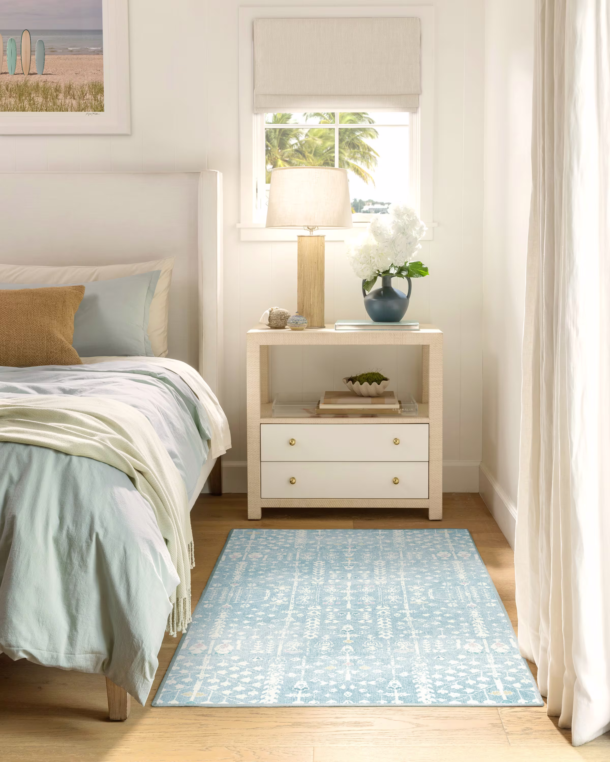 Blue coastal-style rug placed on light hardwood flooring in a bedroom, complementing a bright and airy interior.