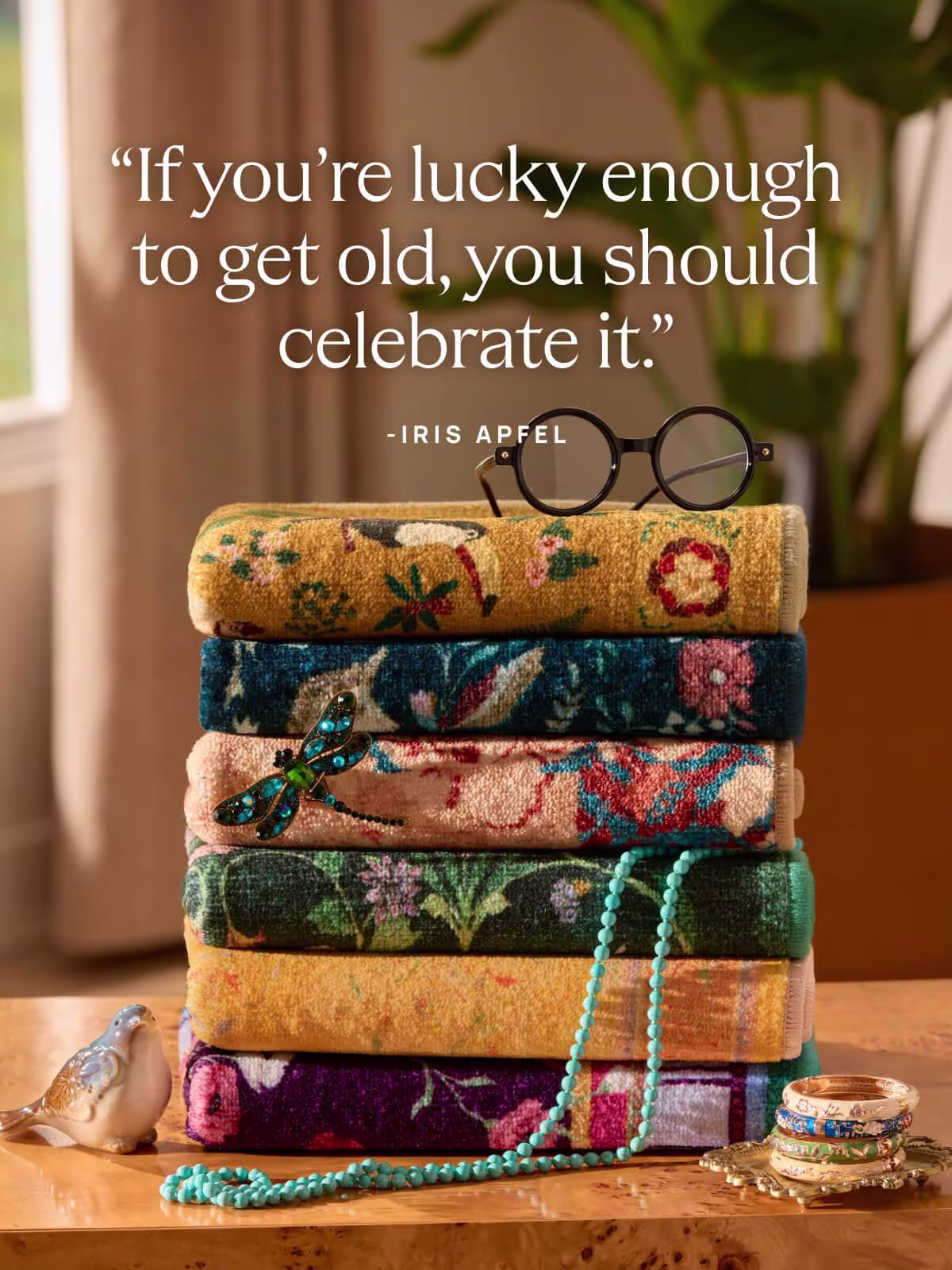 Image of a stack of Ruggable x Iris Apfel rugs and black-rimmed glasses with a text overlay, "If you're lucky enough to get old, you should celebrate it."