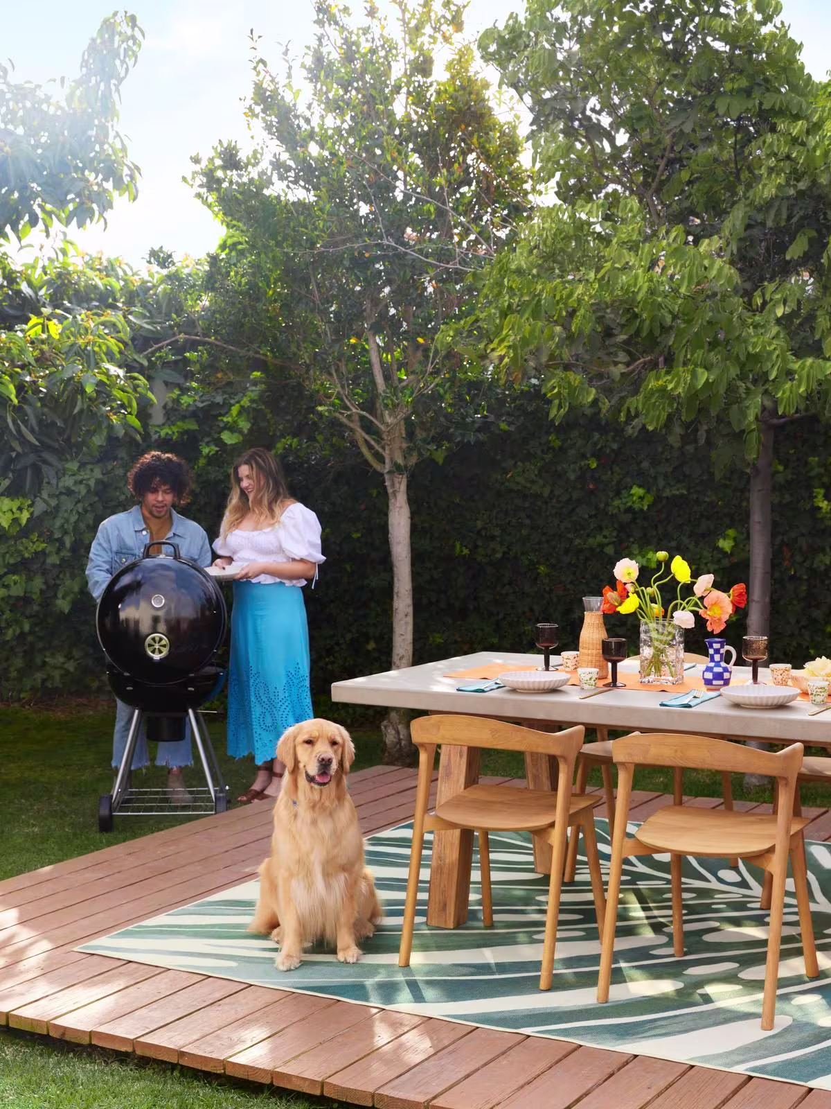 Ruggable Outdoor Panama Jade Rug in outdoor dining setting with outdoor grill, summer tablescape, and golden retriever dog
