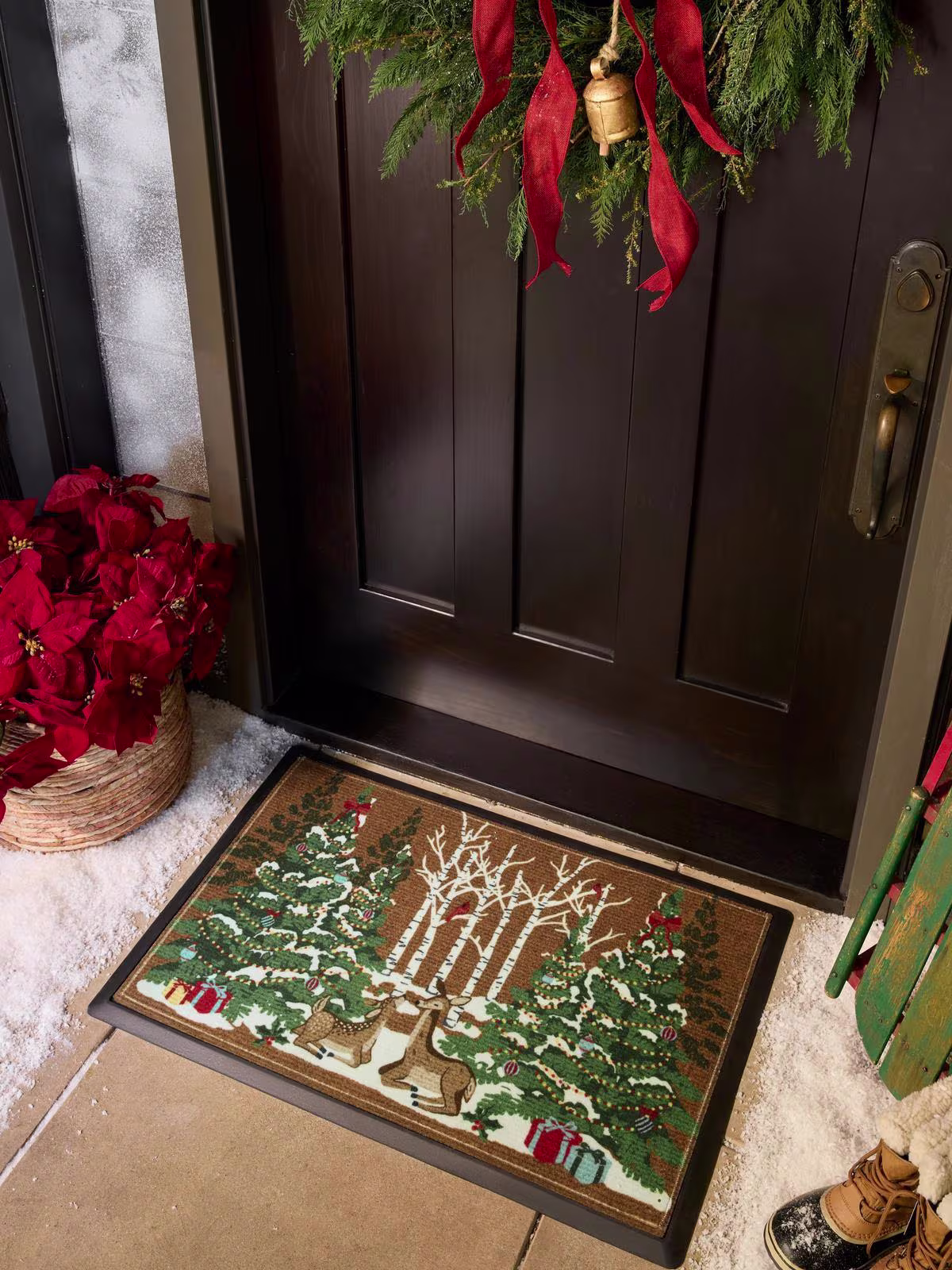 Image of a holiday-themed doorstep with a wreath, red bow, and the Ruggable Woodland Holiday Doormat.