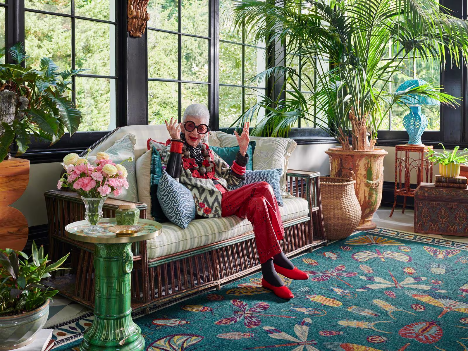 Iris Apfel sits in her vibrant living room with our Ruggable x Iris Apfel Flutterby Rug

