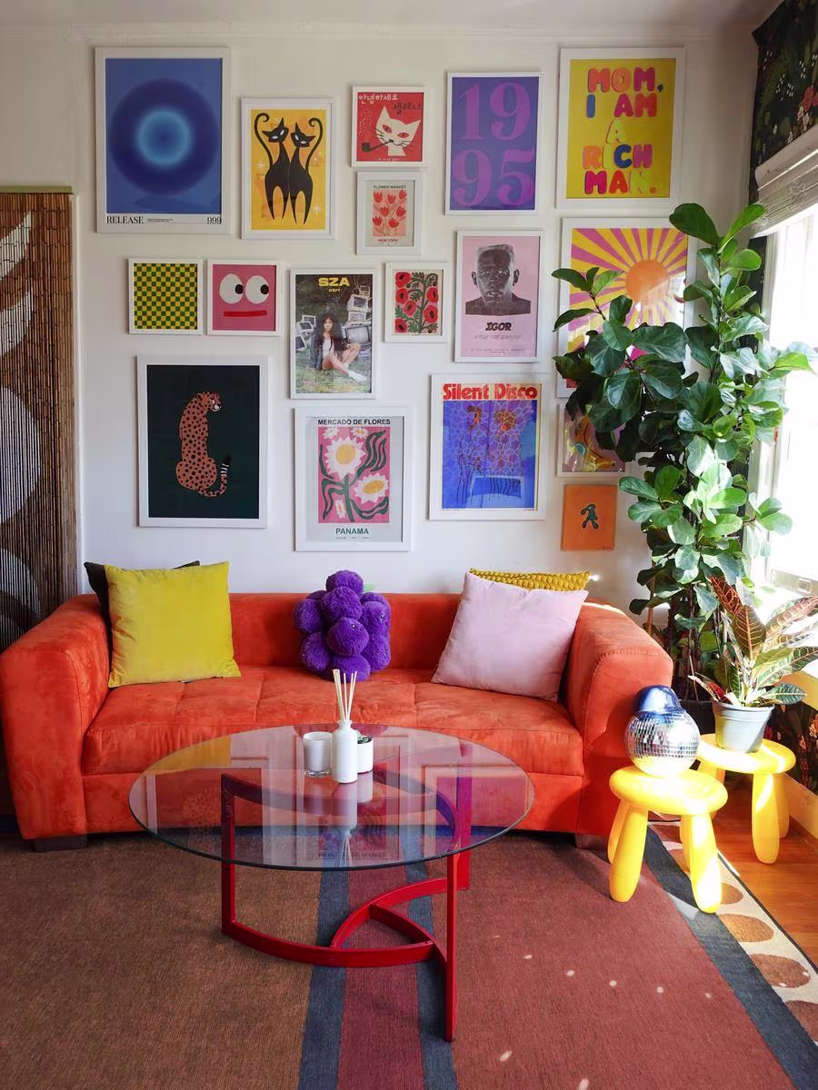 Celenabrownie living room with colorful gallery wall, discoball, house plants, glass coffee table, orange couch, and washable Ruggable x Justina Blakeney Nina Indigo & Rust rug