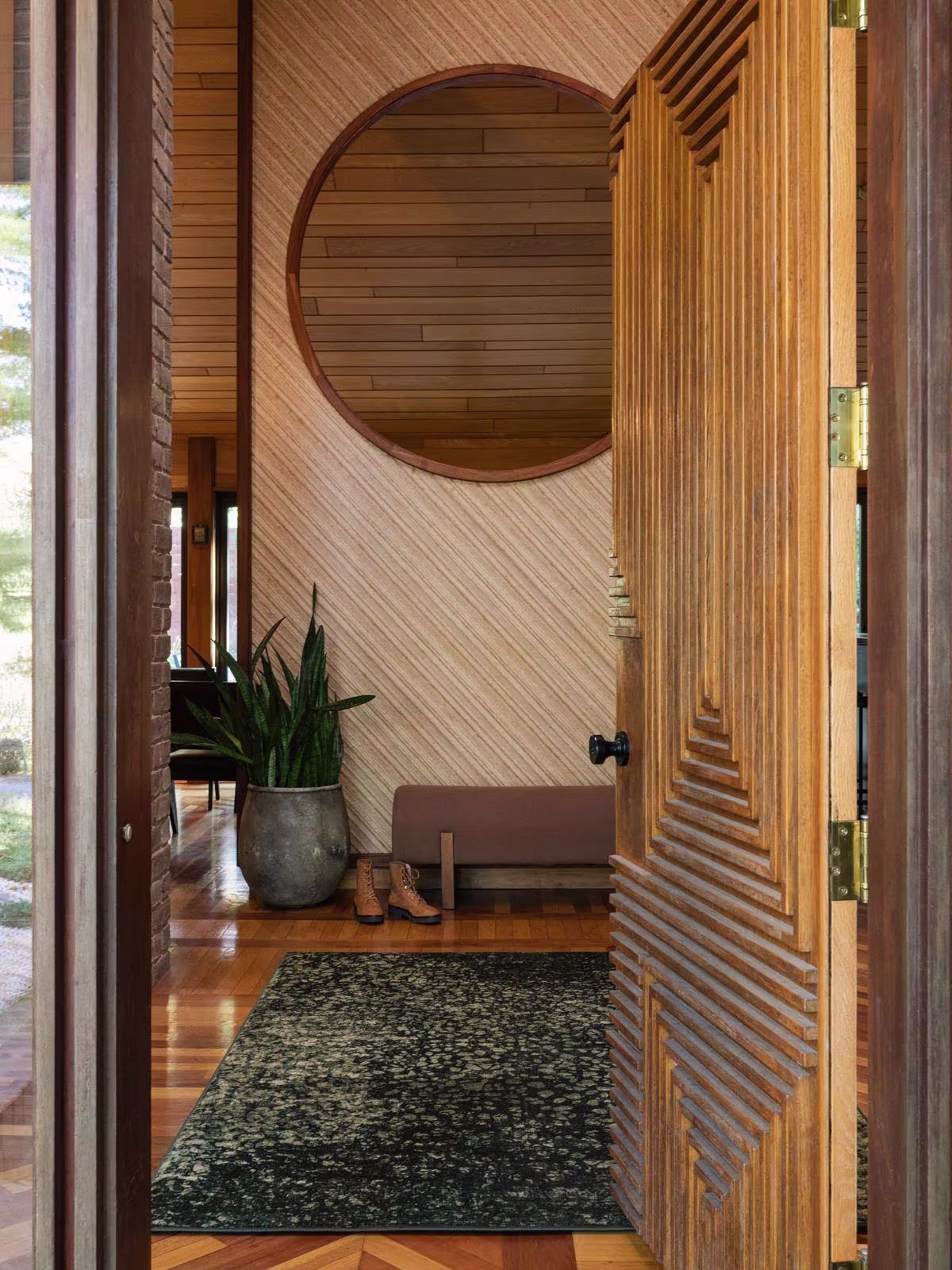 Image of a home entryway with wooden accents, weathered textures, and the Ruggable x Architectural Digest Terran Moss Rug. 