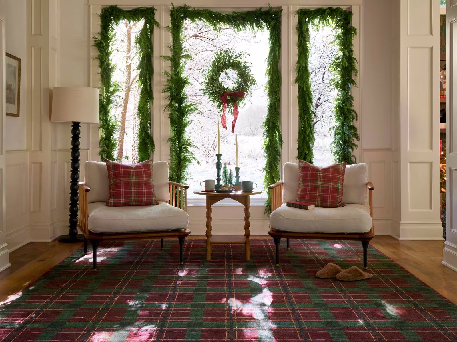 Image of a sun-filled reading room with comfy chairs and evergreen garlands on the windows and Ruggable's Piper Plaid Burgundy & Green Rug.
