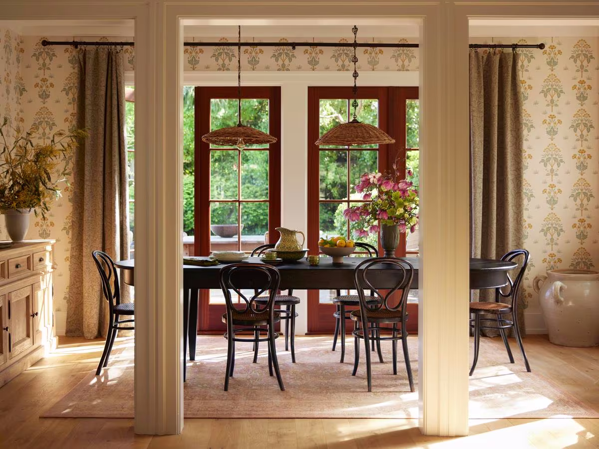 Cottagecore dining room with pillars, black table, Morris & Co. wallpaper and rug