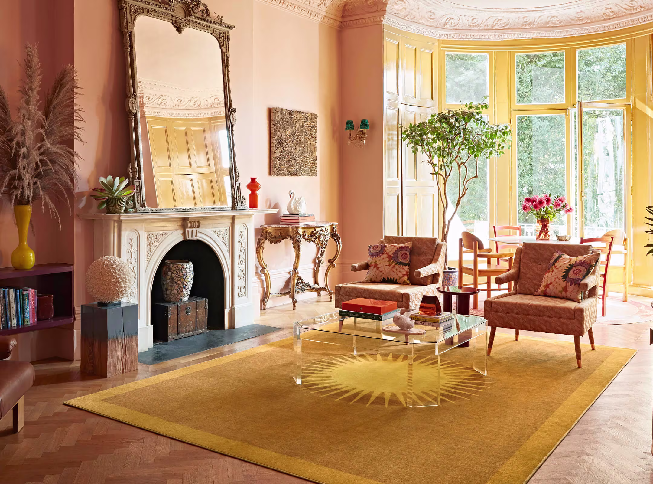 Colour drenched living room with warm peach walls and a Helios Gold Rug by Matthew Williamson anchoring the space with bold, sun-inspired pattern and tone.