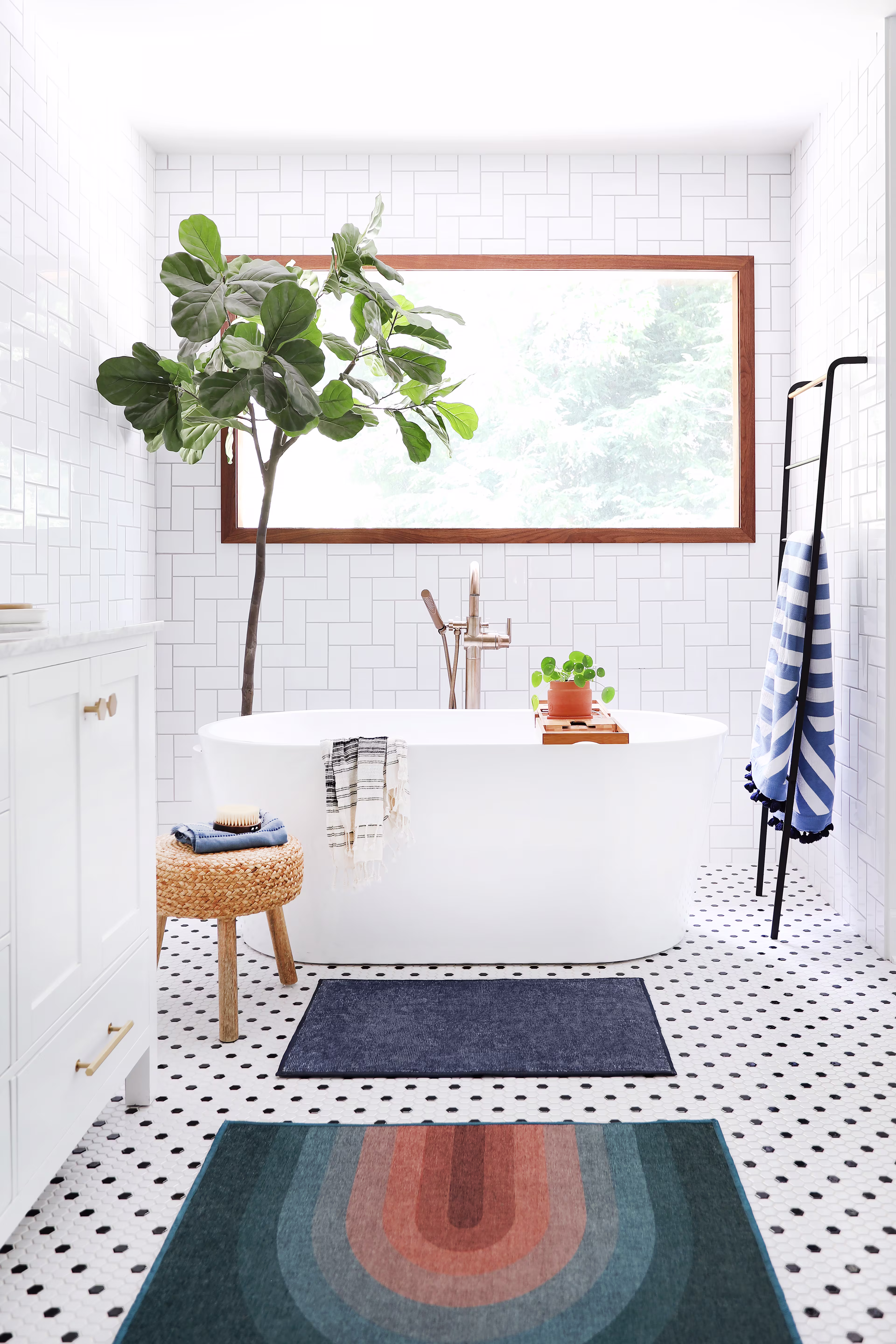 Ruggable Absida Teal bath mat and Solid Navy Blue bath mat styled in a bright modern bathroom with a freestanding tub, white subway tile, and a fiddle-leaf fig tree.
