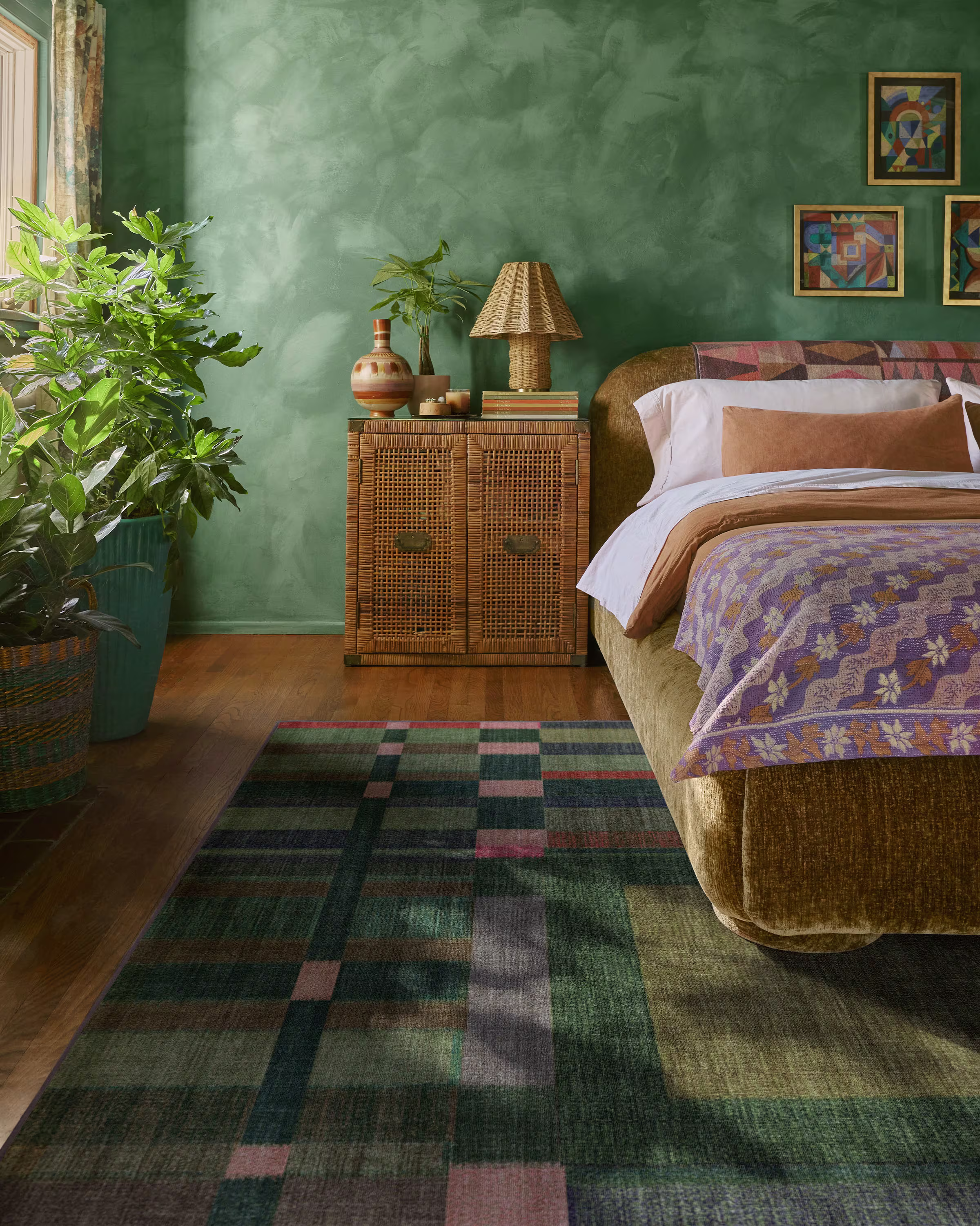 Ruggable x Jungalow Lad Olive green geometric area rug in a bohemian styled bedroom next to a velvet upholstered bed.