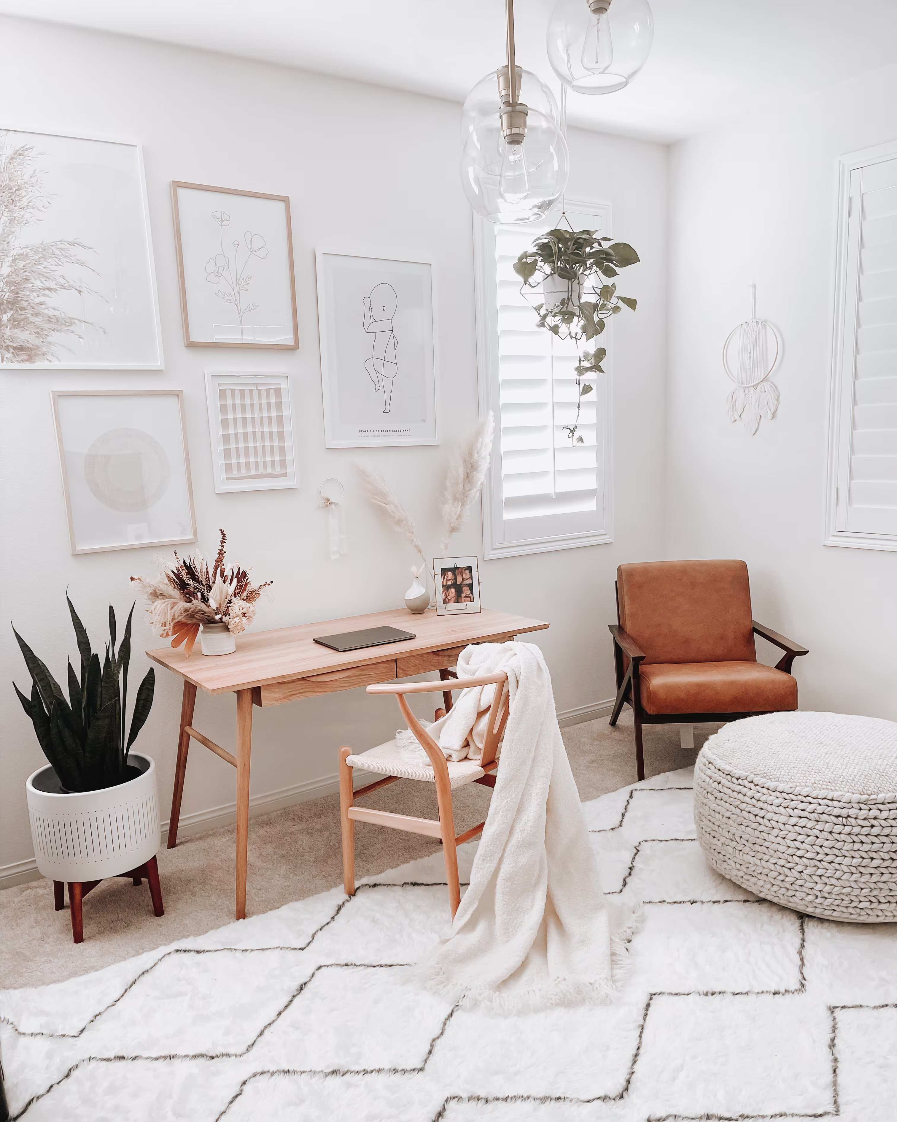 Bright boho home office featuring a white Moroccan shag rug with dark diamond patterns, light wooden desk, leather armchair, and framed wall art.