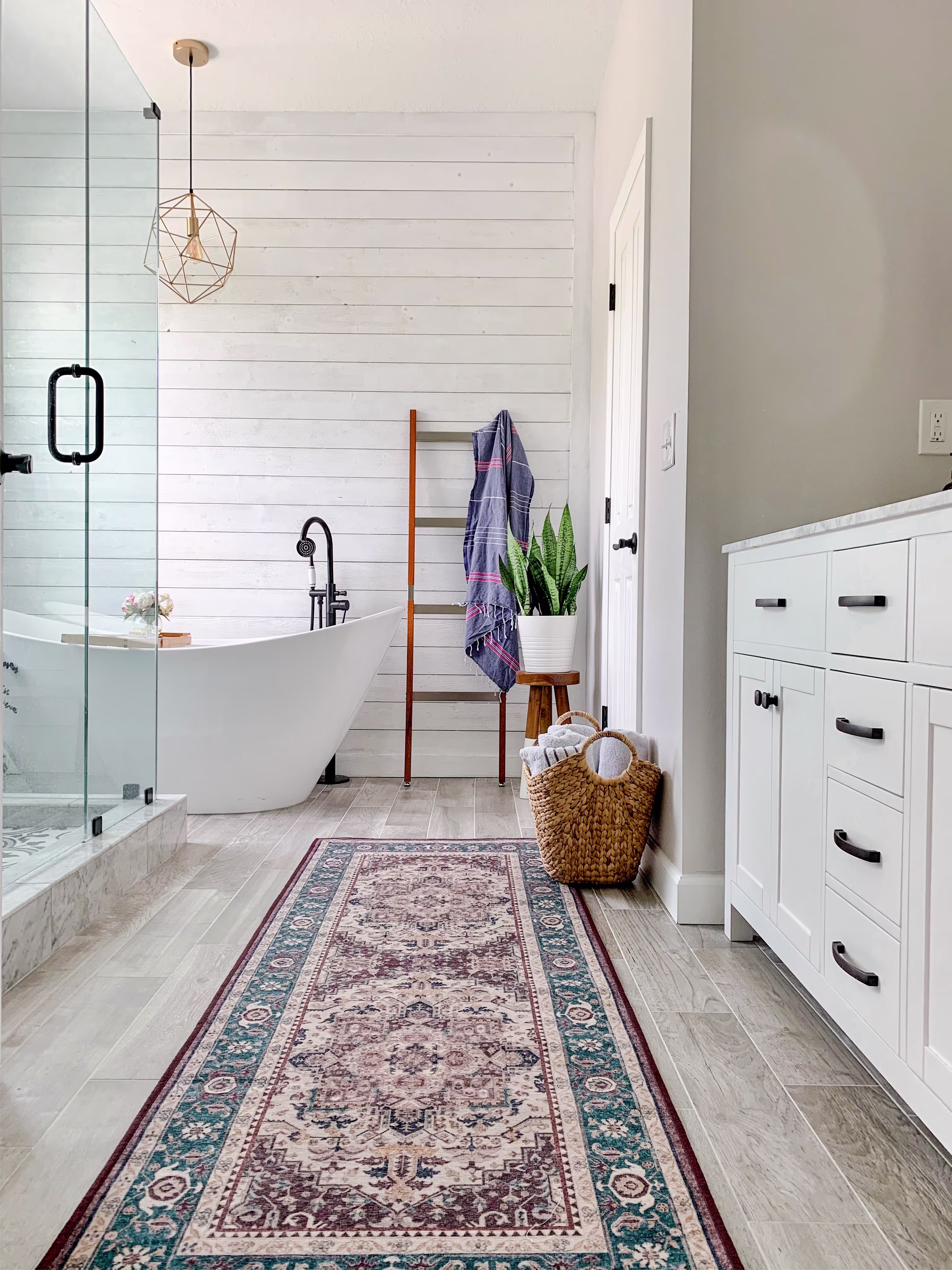 Vintage Heriz Ruby traditional runner rug styled in a bright farmhouse bathroom next to a freestanding white bathtub and white vanity.