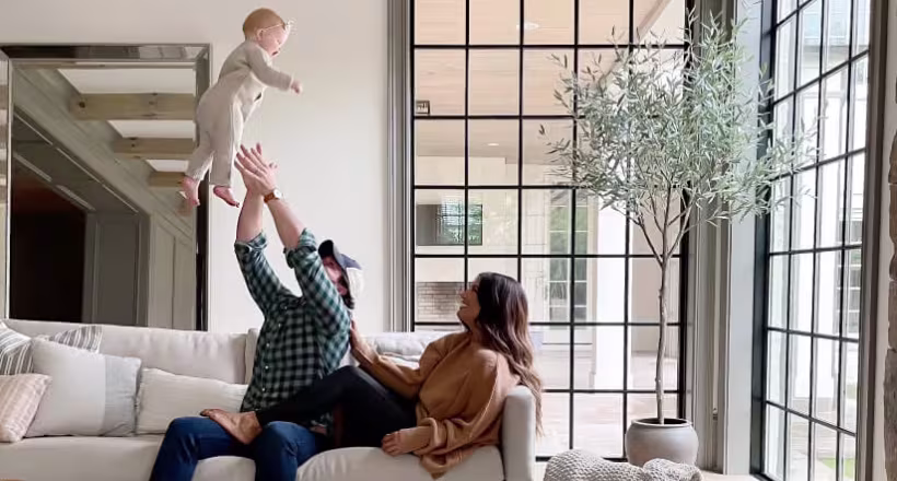 Family lounging on a couch in their living room near a large corner window