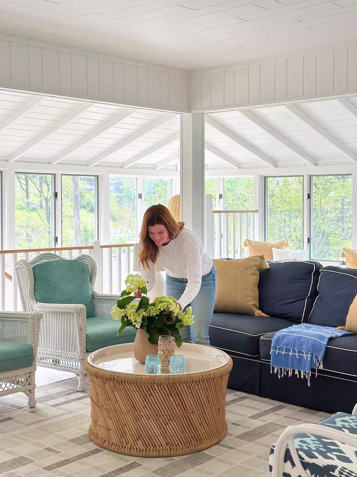 Ruggable x The Home Edit Miles Natural Rug in sun-soaked living room with wicker furniture and fresh hydrangea floral arrangement