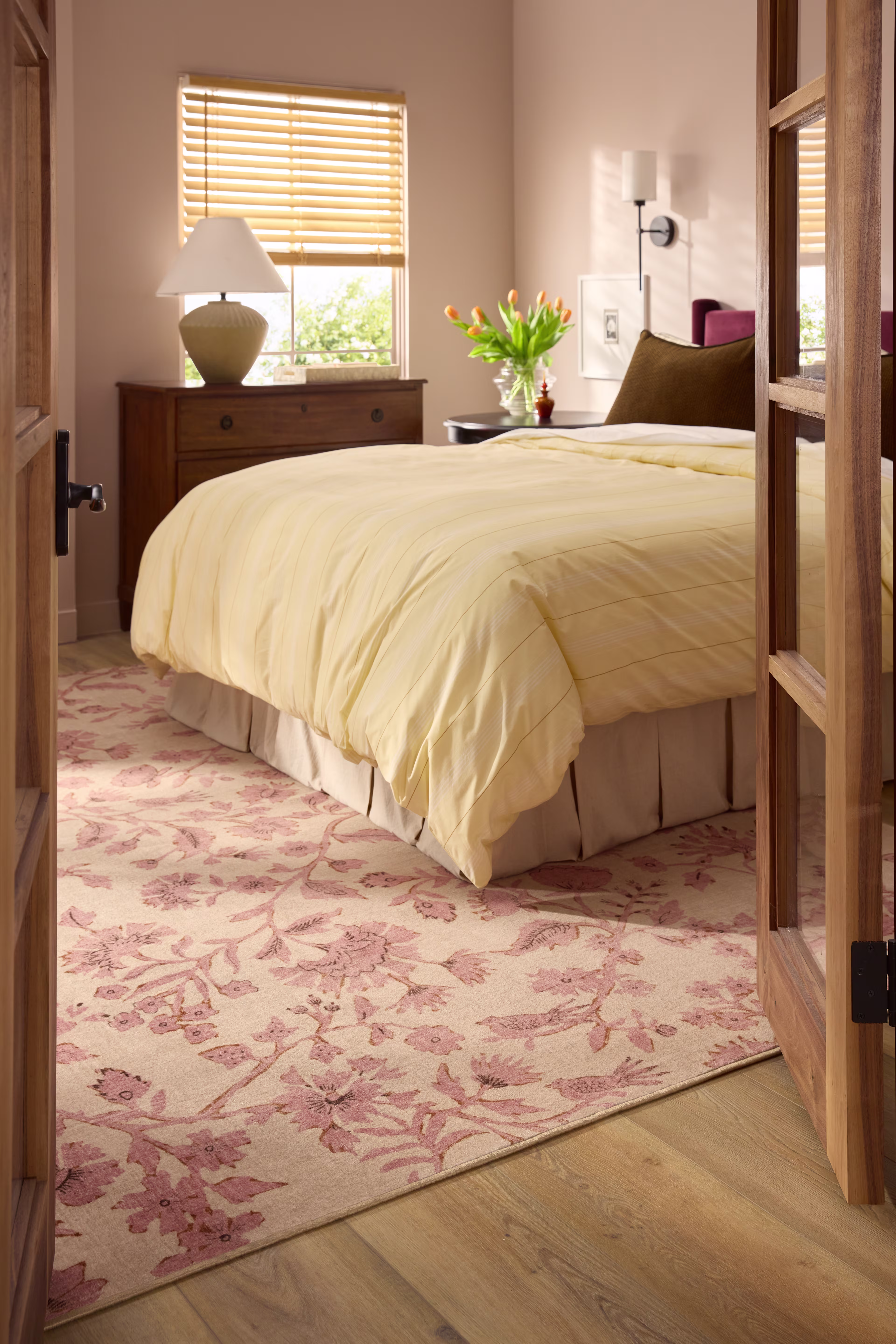Pink and red floral rug placed underneath a bed, adding a soft decorative accent to a bedroom space.