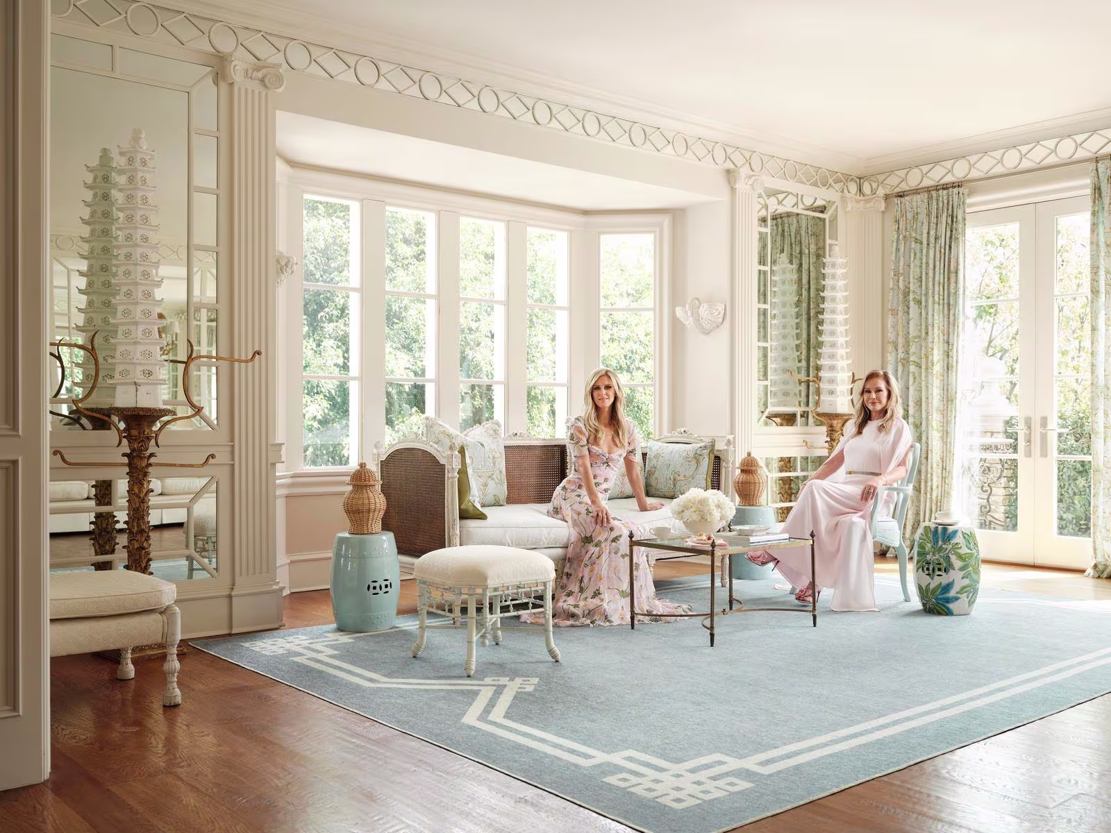 Kathy & Nicky Hilton sit in Kathy's living room with luxurious, chic decor and washable area rug from their Ruggable x The Hiltons Collection