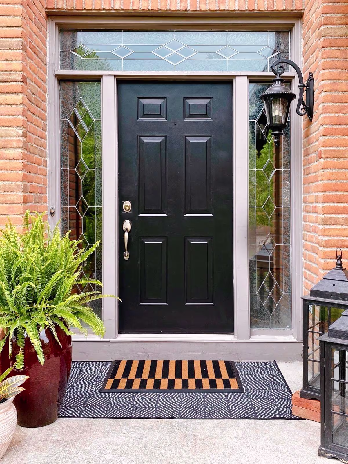 Image of a front door featuring two sizes of rugs layered on top of one another. A larger printed outdoor rug, and a smaller Alterna Stripe Doormat.