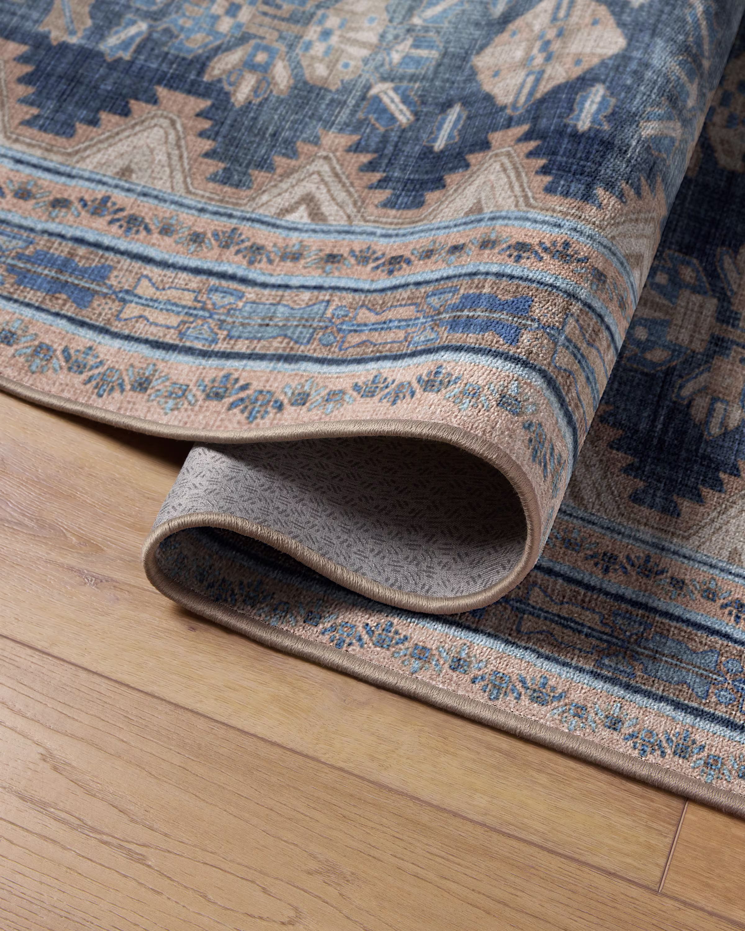 Close-up of a blue patterned washable rug on a light hardwood floor, showing texture and design detail
