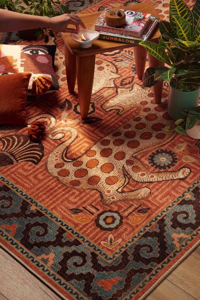 Ruggable x Justina Blakeney Eartha Terracotta washable rug with throw pillows, house plants, and incense. 