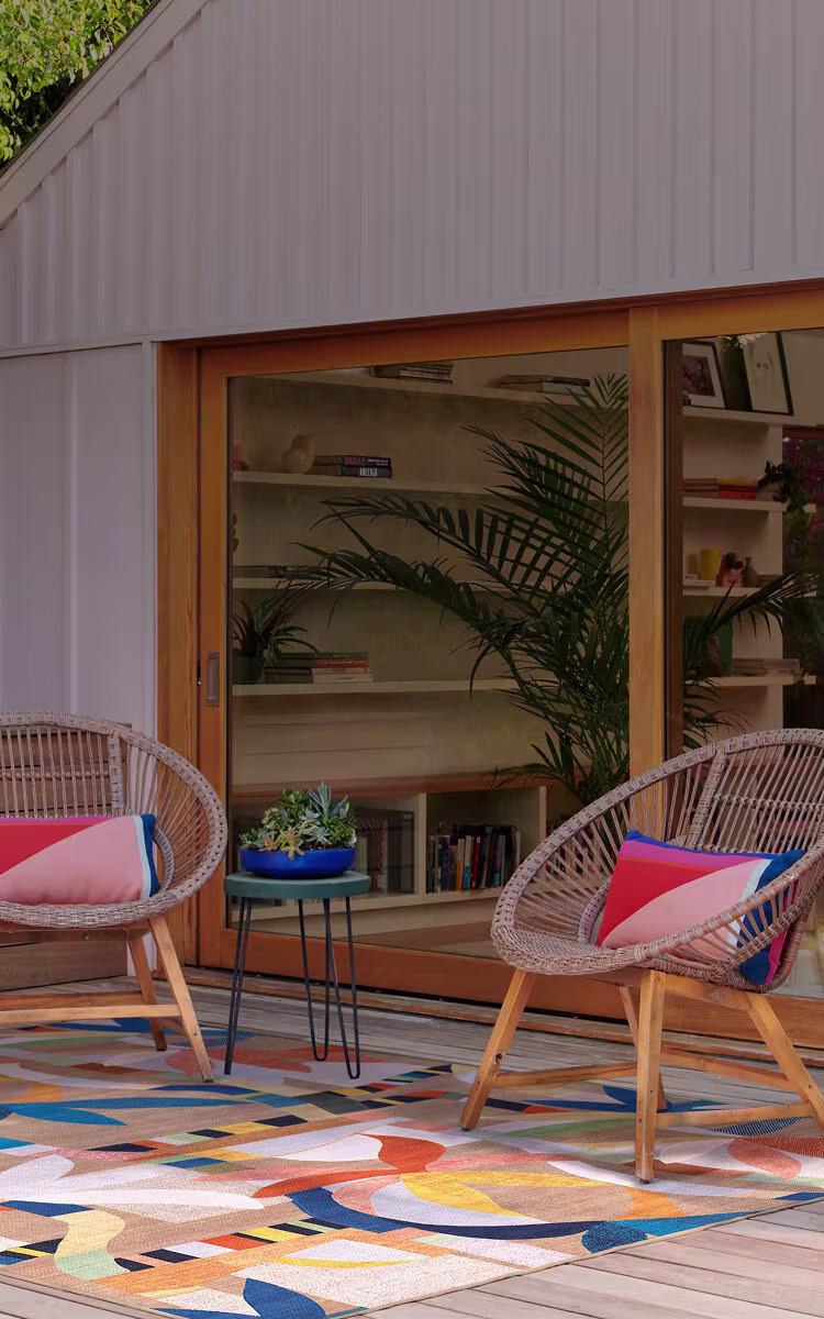 Home patio with a bright colorful outdoor rug styled with modern furniture and natural light