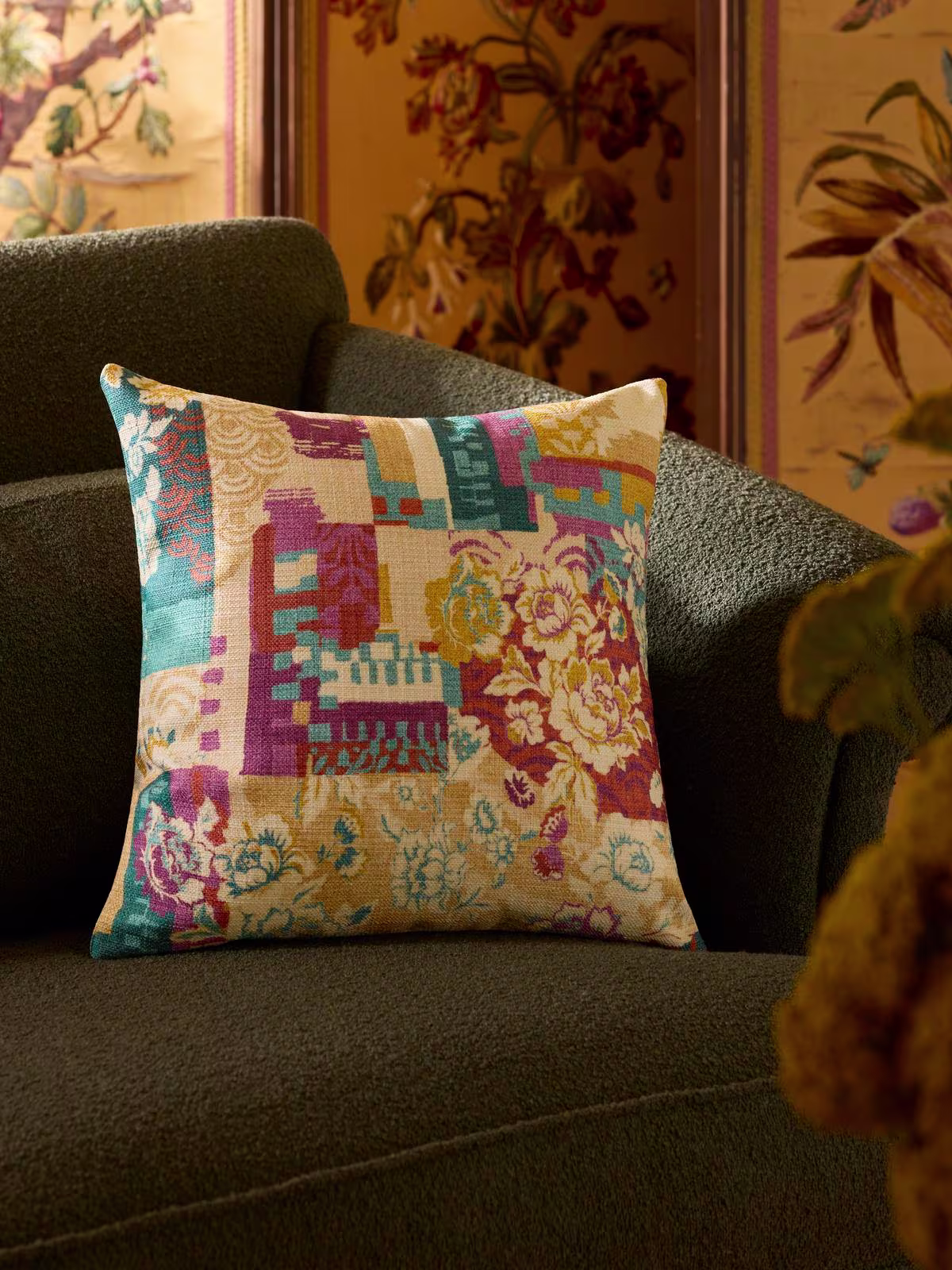 Image of forest green sofa with the Iris Apfel Remix Jewel Multicolor Woven Throw Pillow. 