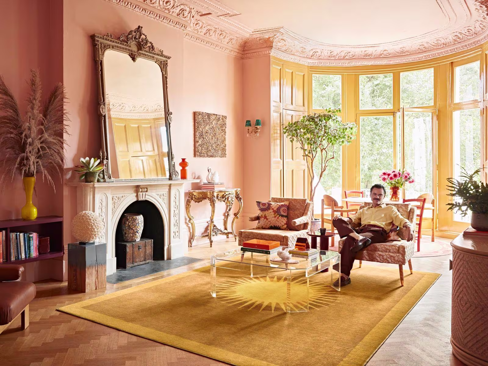 Interior designer Matthew Williamson sits in his colorful living room with our washable Helios Gold Rug

