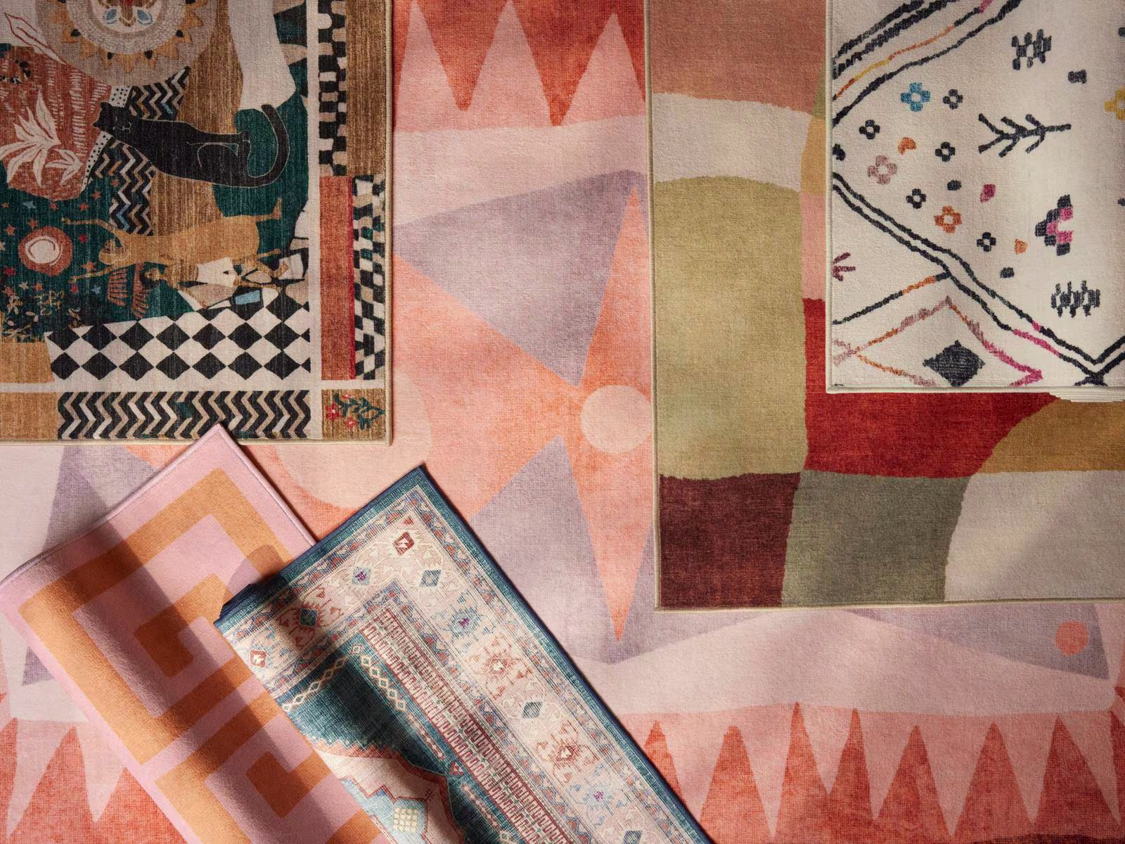 An image from above of rugs layered together featuring a mixture of colors, patterns, sizes, and textures. 