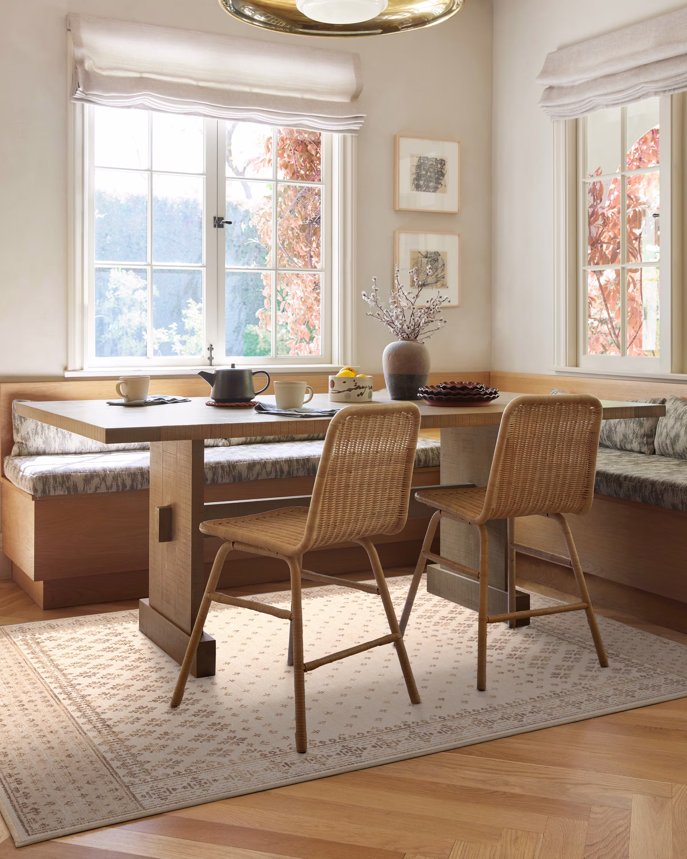 Cozy breakfast nook with a wooden table, two wicker chairs, and cushioned bench seating. Soft natural light streams through a window, creating a serene atmosphere.