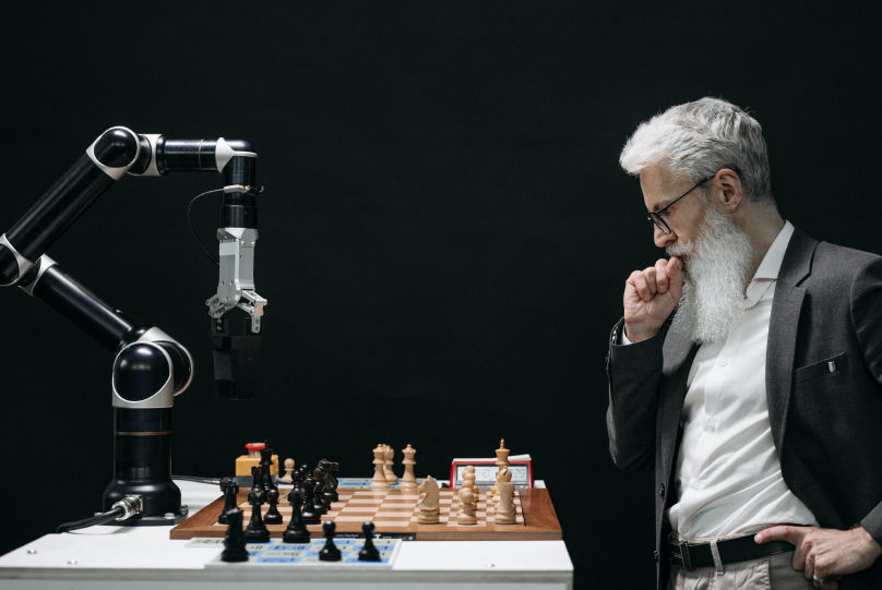 a man playing chess in front of a robot