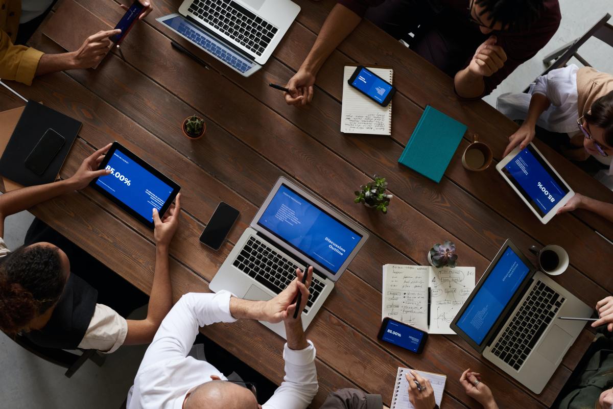 a group of people sitting around a table with laptops