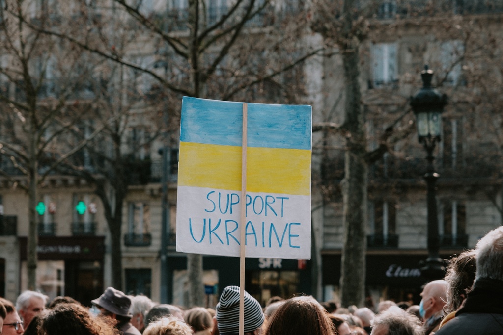 a large group of people standing around a building with Ukrainian flag