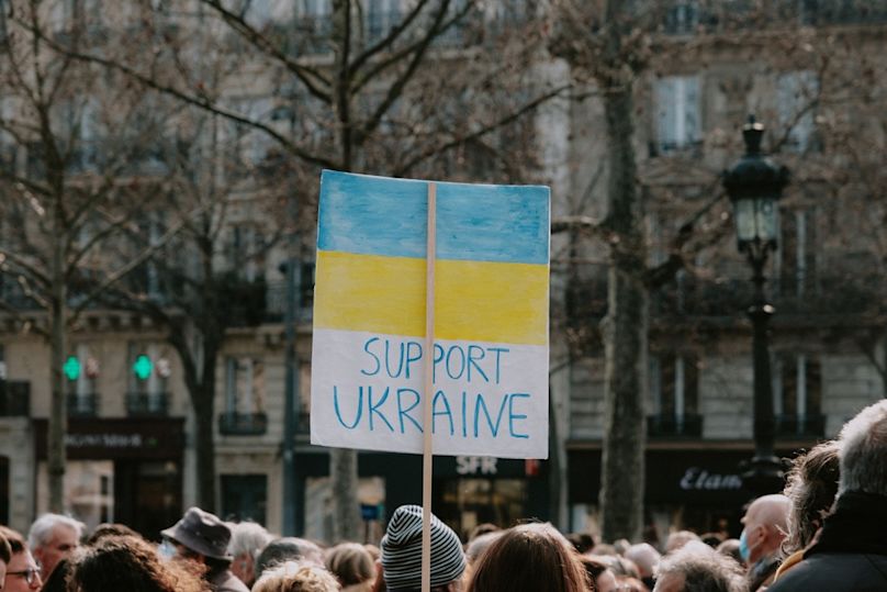 a large group of people standing around a building with Ukrainian flag