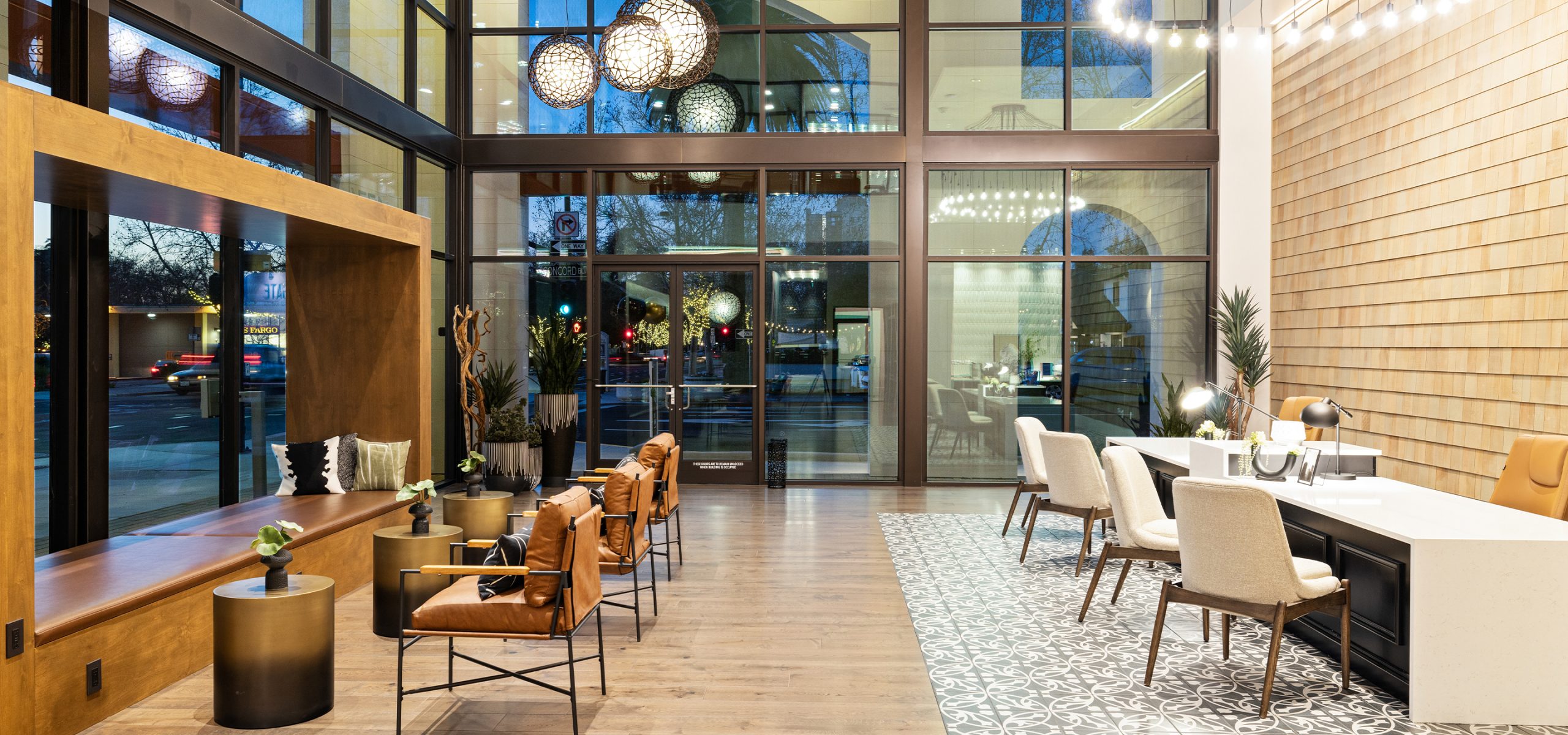Interior view of The Grant’s leasing lobby with floor-to-ceiling windows, designer lighting, and warm wood finishes that reflect upscale urban living.