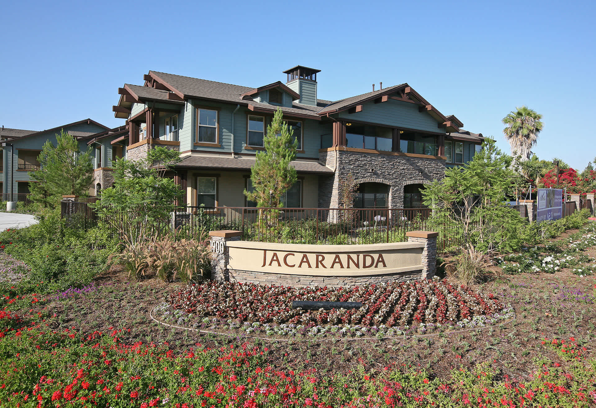 Craftsman-style senior living community in Orange County, CA with rich landscaping and natural stone details—offering 1 & 2-bedroom apartments for residents aged 55+.