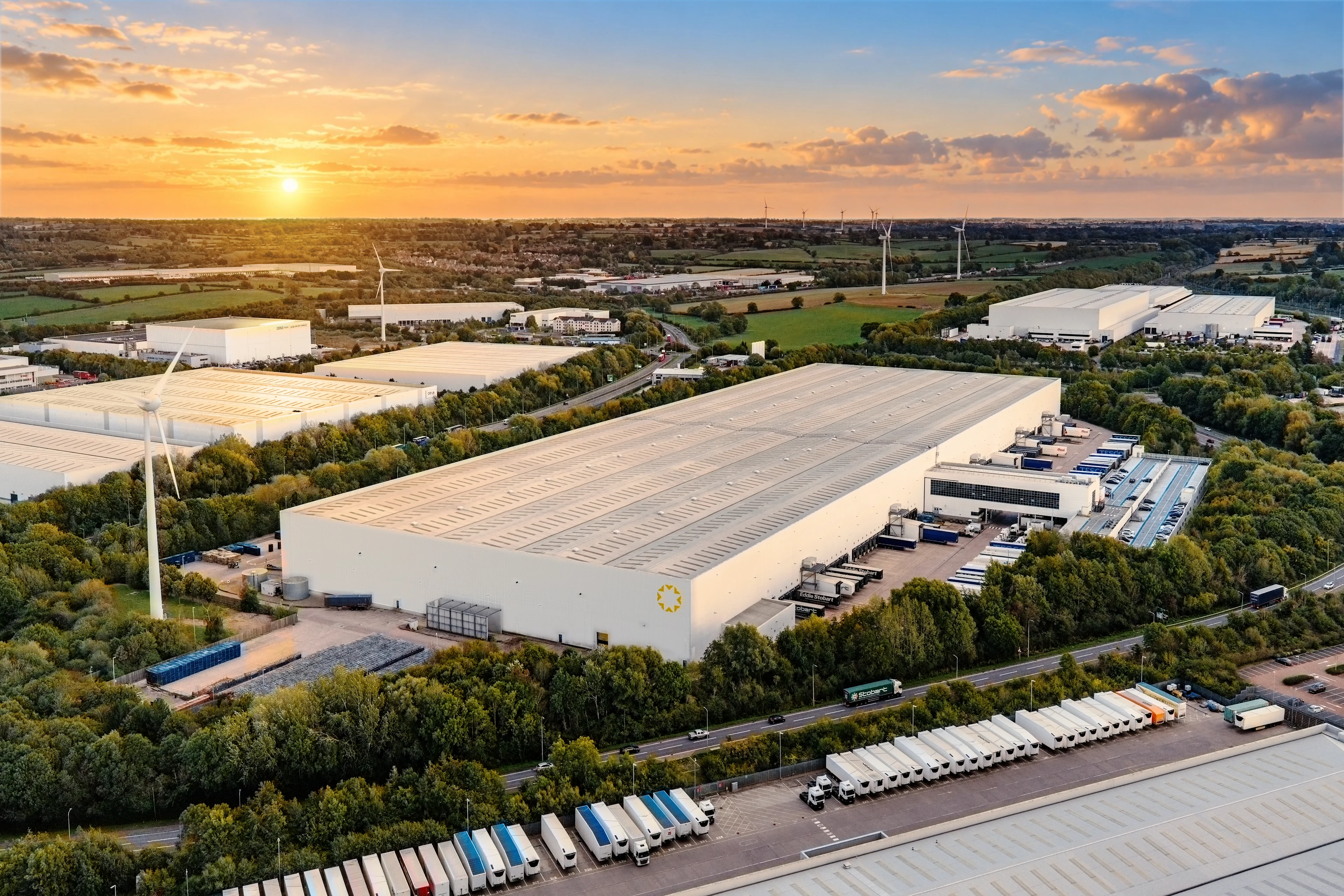 Logistics distribution center at sunrise with trucks at loading docks