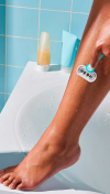 Woman shaving her leg with a blue razor