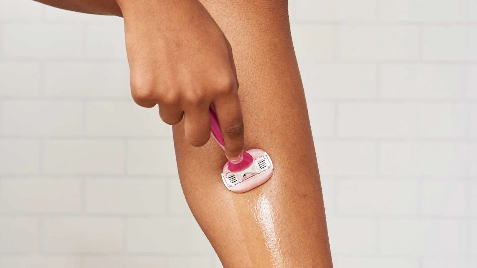 Woman shaving her leg with a pink razor