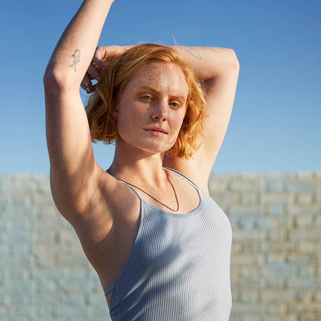 Girl holding hands up showing armpits outside in sunlight