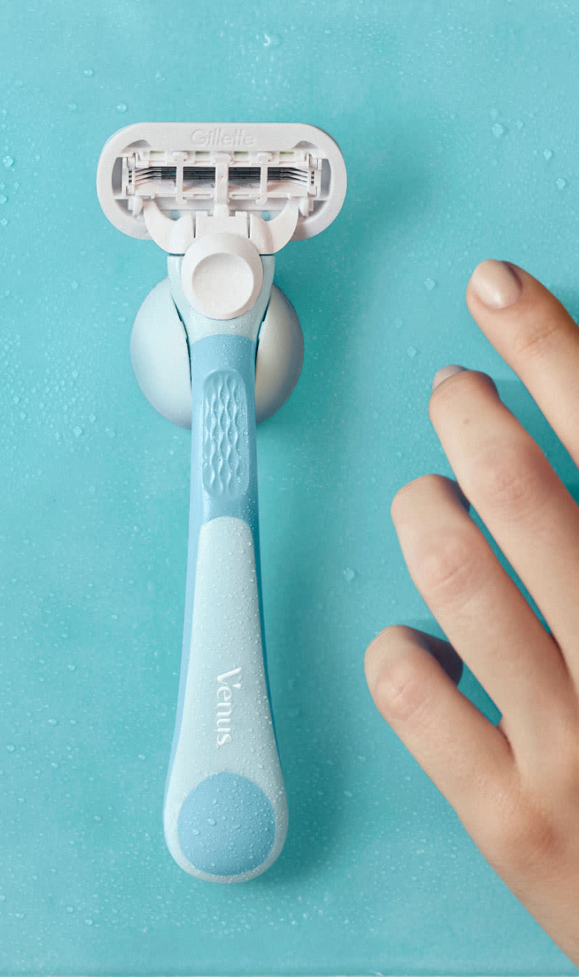 Hand reaching out to take the Extra Smooth razor attached to the shower holder on a wall