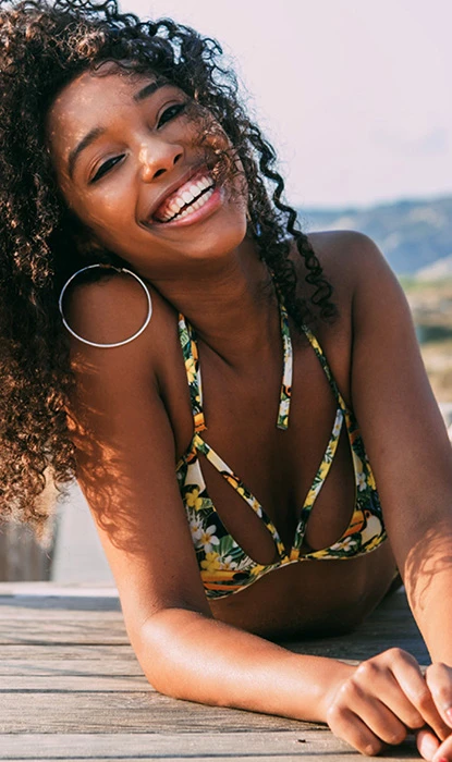 Young lady smiling, while laying on a wooden plateau, on a clear, sunny day