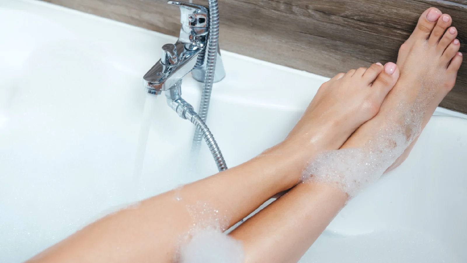 Legs covered in foam in a bathtub
