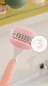 Pink-coloured refillable Gillette Venus razor with a focus on its razor head and 3 blades