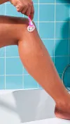 Woman shaving her leg with a pink razor