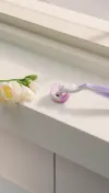 Purple refillable Gillette Venus razor next to flowers on a surface