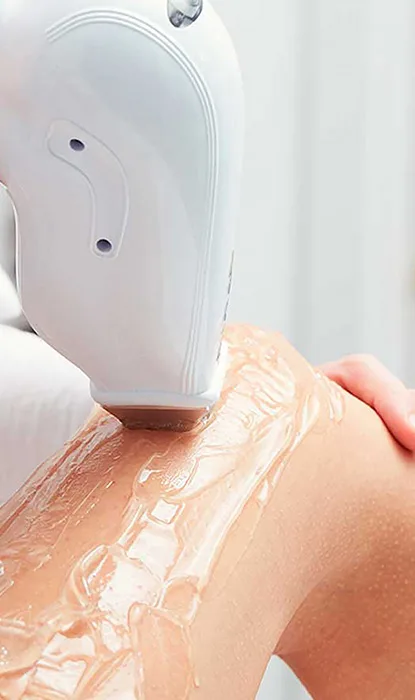 A person using a laser hair removal device on the upper leg