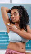 Woman shaving her underarm area with a silver razor