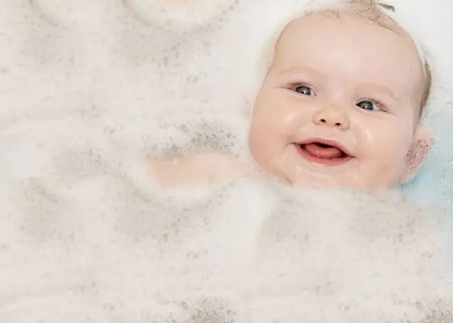 bebé recién nacido sonriendo en la hora de baño