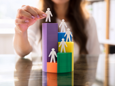 Hand staking plastic people on blocks of varying heights and colors