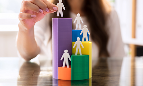 Hand staking plastic people on blocks of varying heights and colors